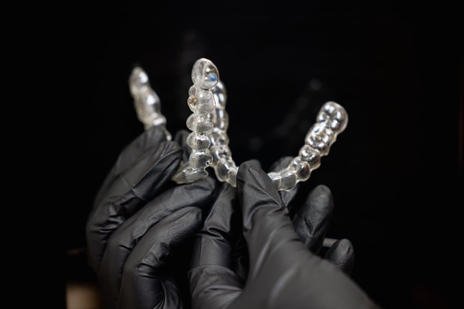 Close-up shot of doctors hands in black gloves holding silicone mouth guard. Teeth care. High quality photo